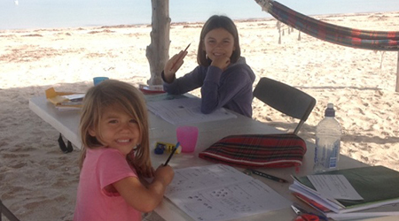 Travelling kids studying at the beach